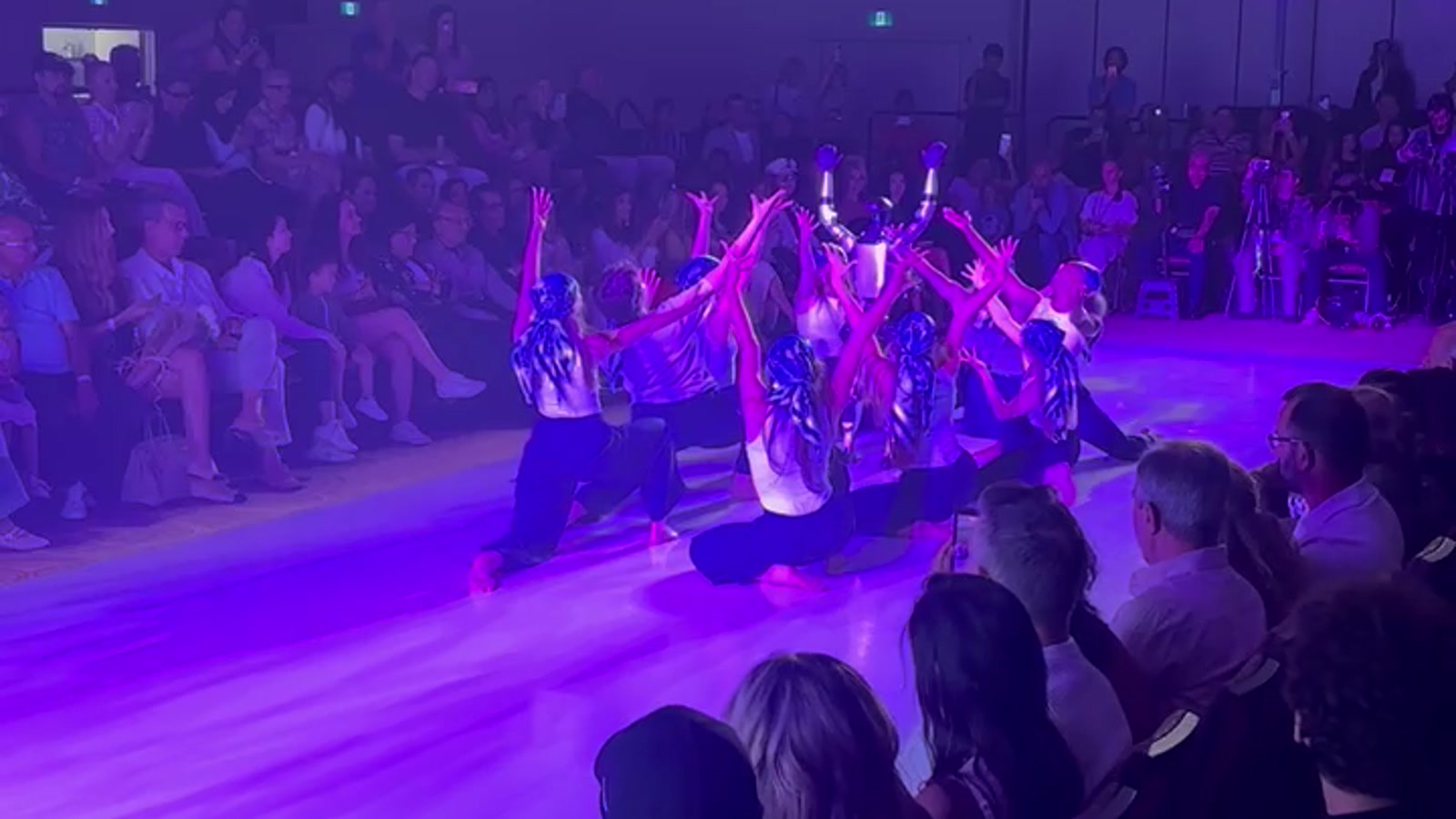 A robot standing centered on a runway with dancers posed around it during a DMA Events activation